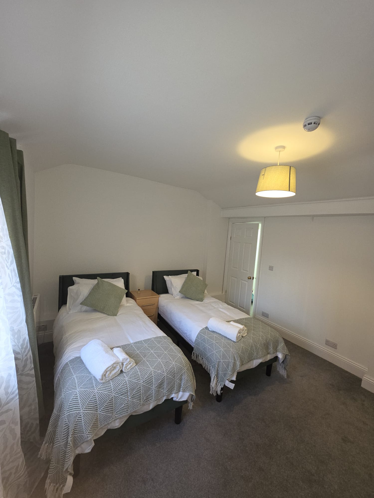 Twin bedroom with crisp white linen and sage green accents