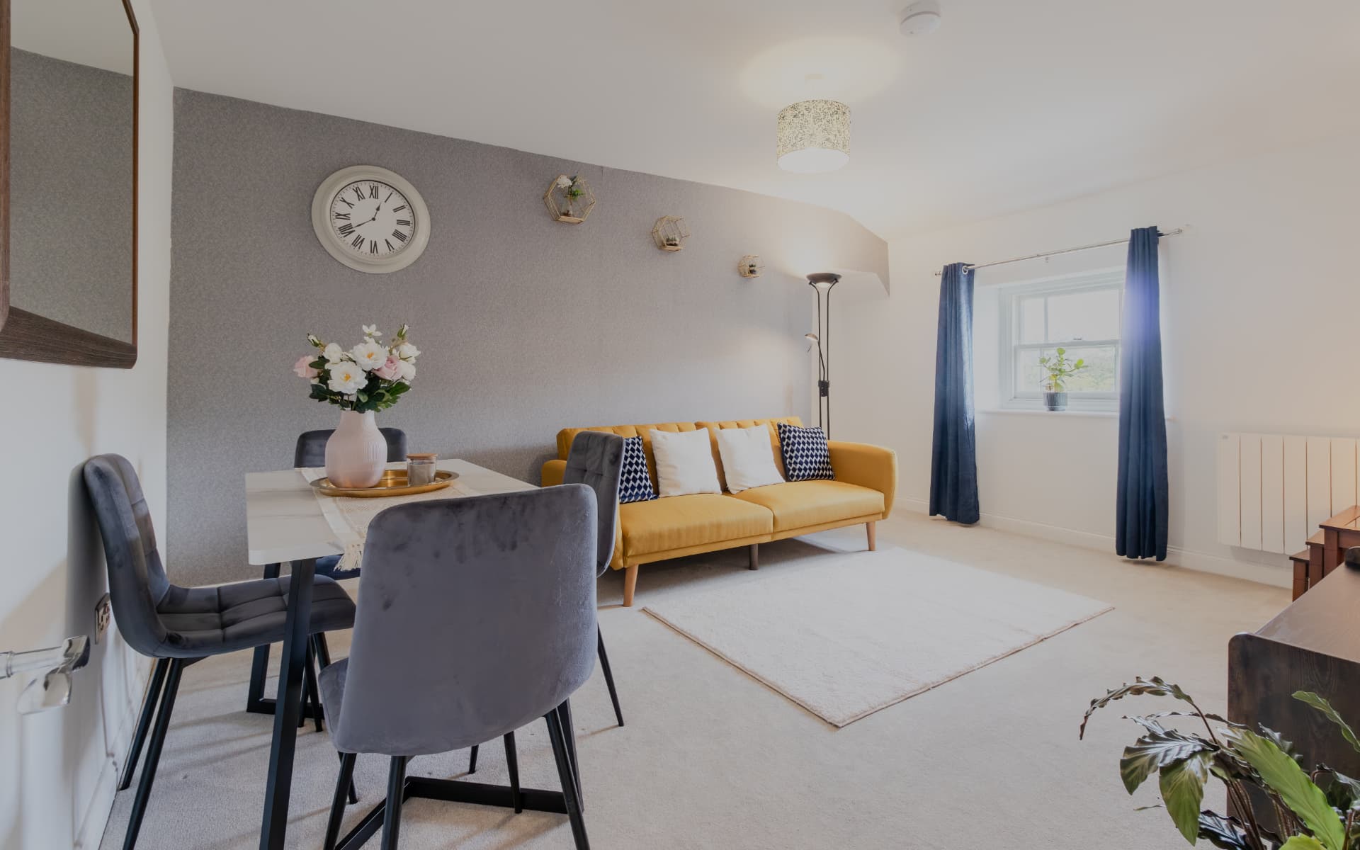 Sitting area with mustard sofa, dining table and navy curtains