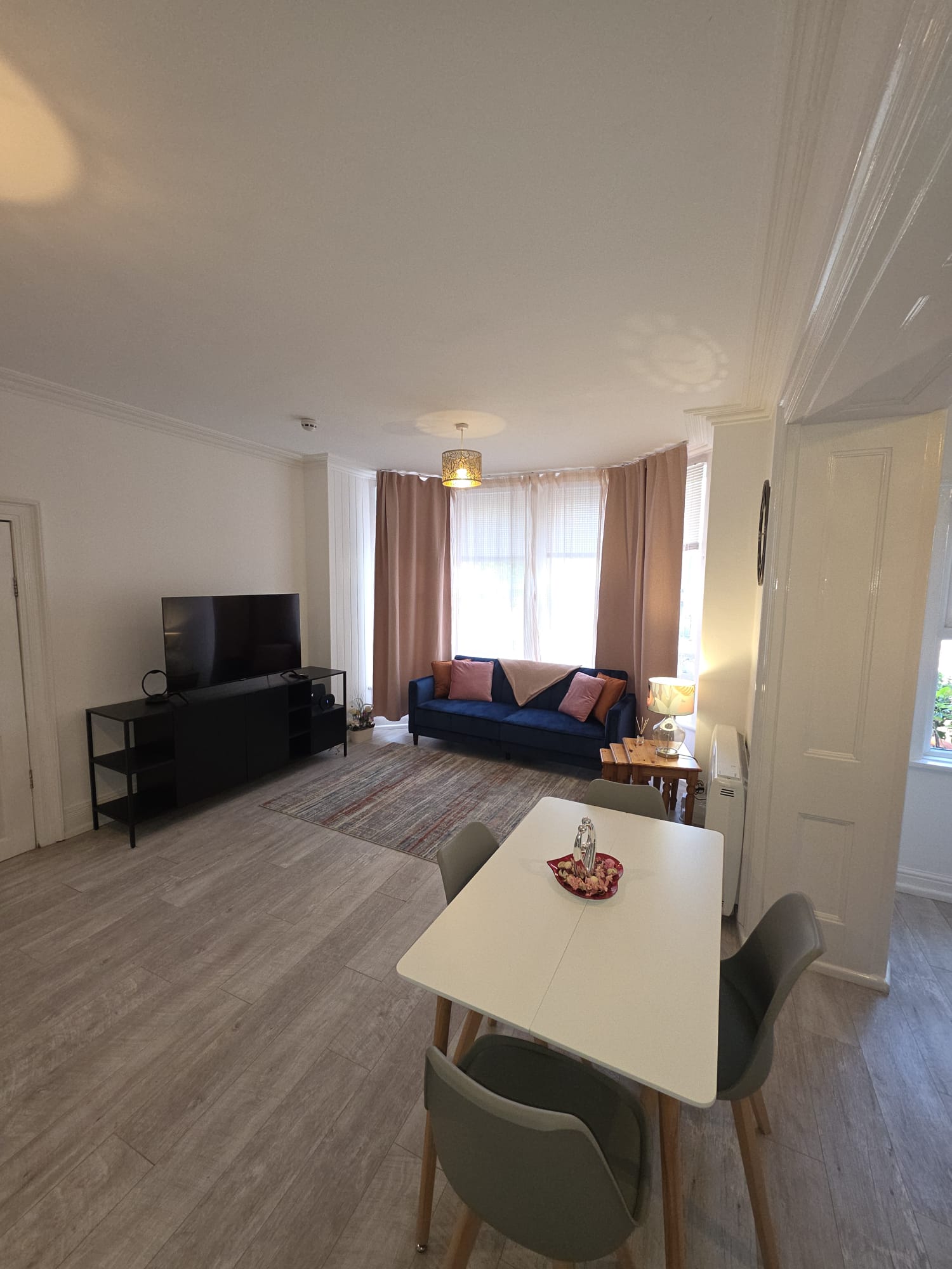Open-plan living area with navy velvet sofa, smart TV and dining table