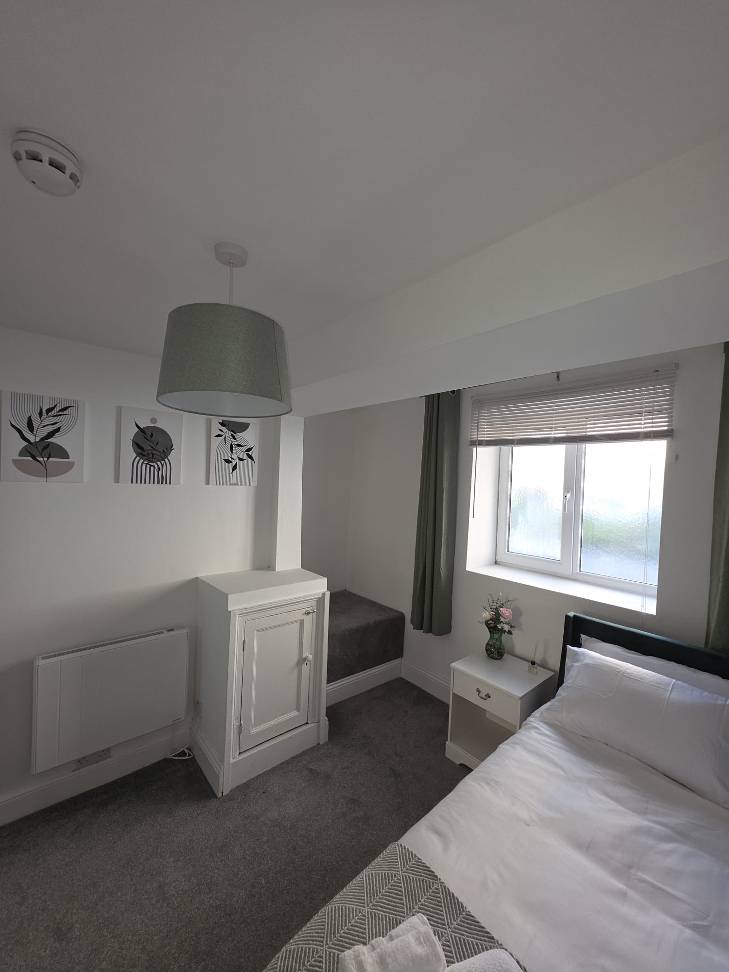 Compact single bedroom with botanical prints and sage pendant shade