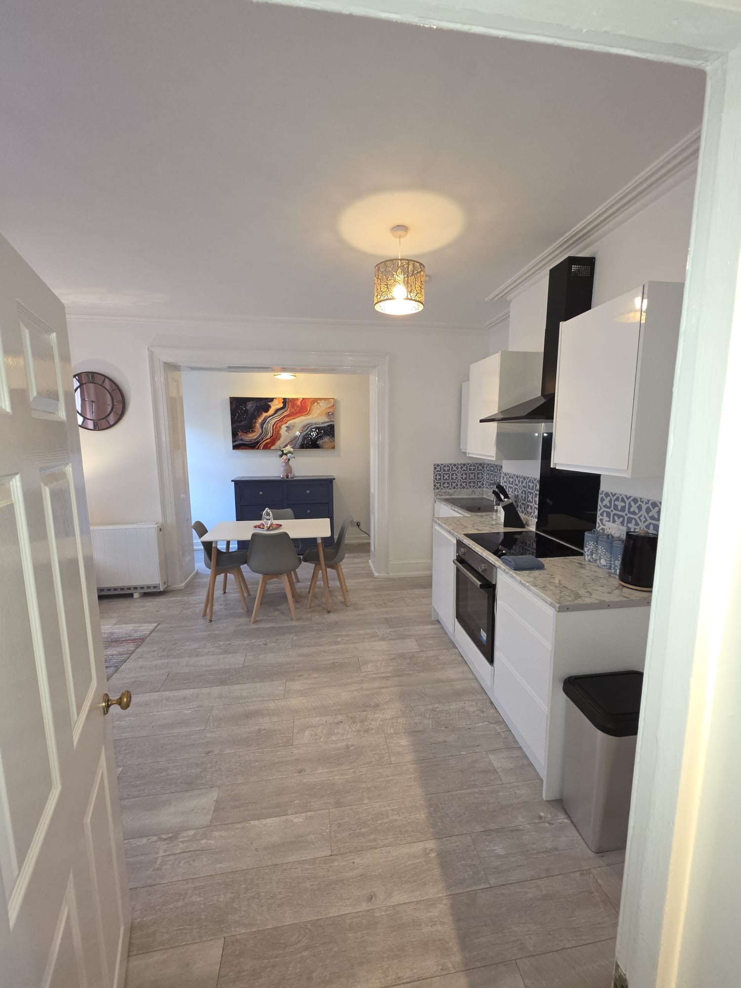 White kitchen with marble worktops, oven, hob and patterned splashback